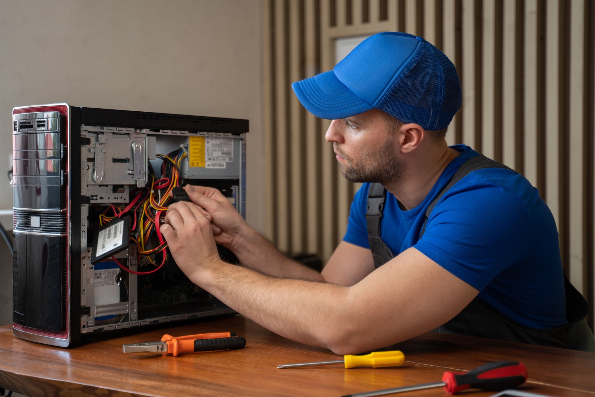 Man in t-shirt repairs computer system unit with screwdriver